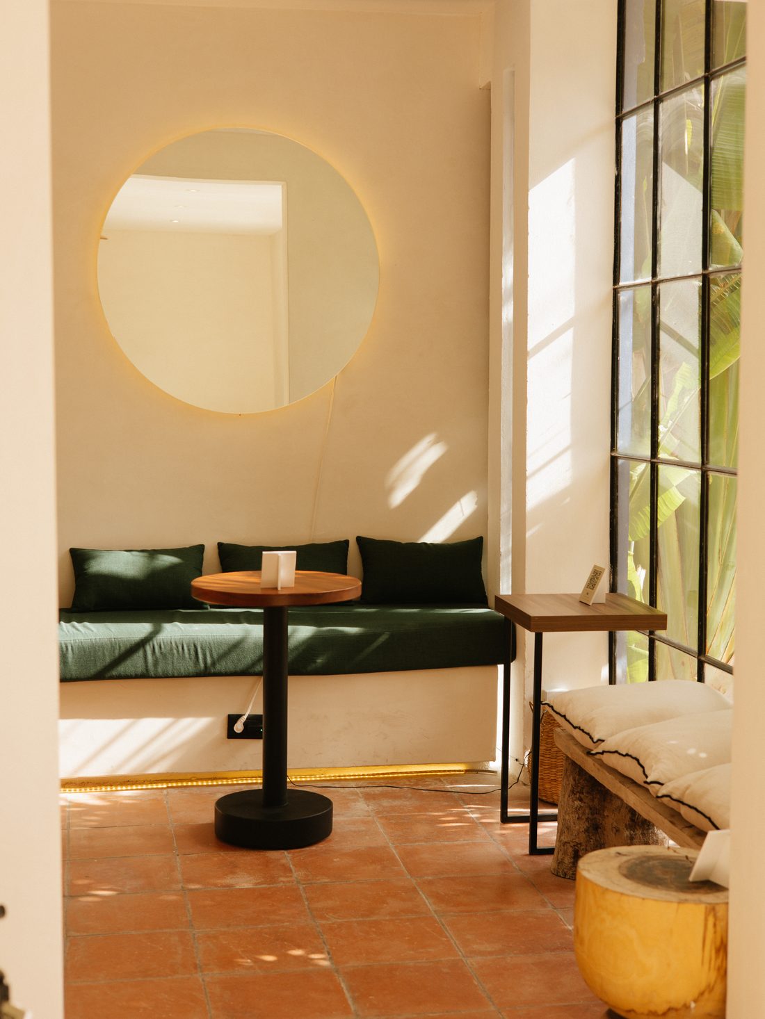 Sala de OLIVO con espejo redondo y banca verde